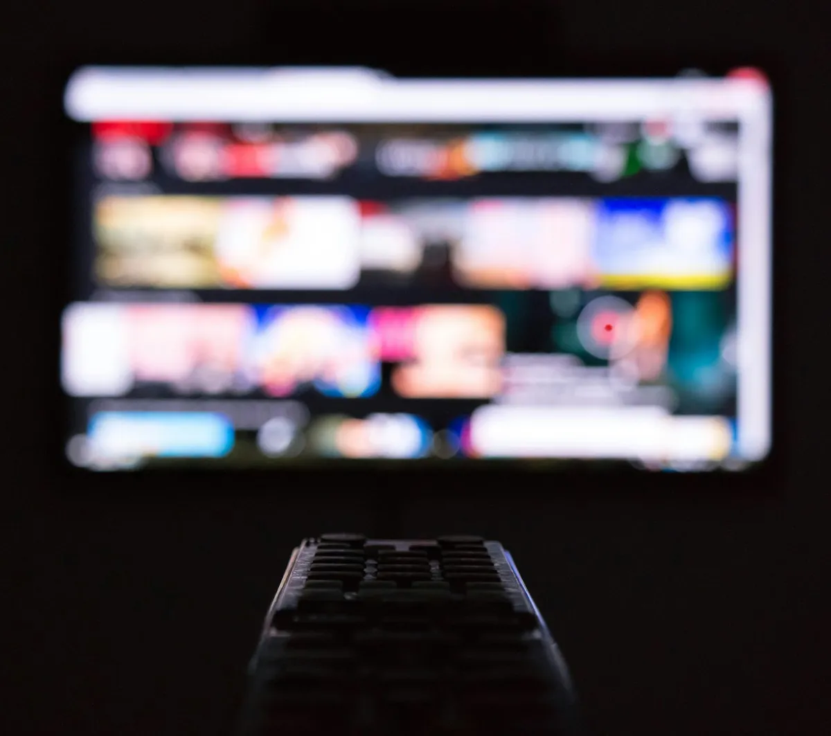 TV remote pointed at a streaming app menu on a television