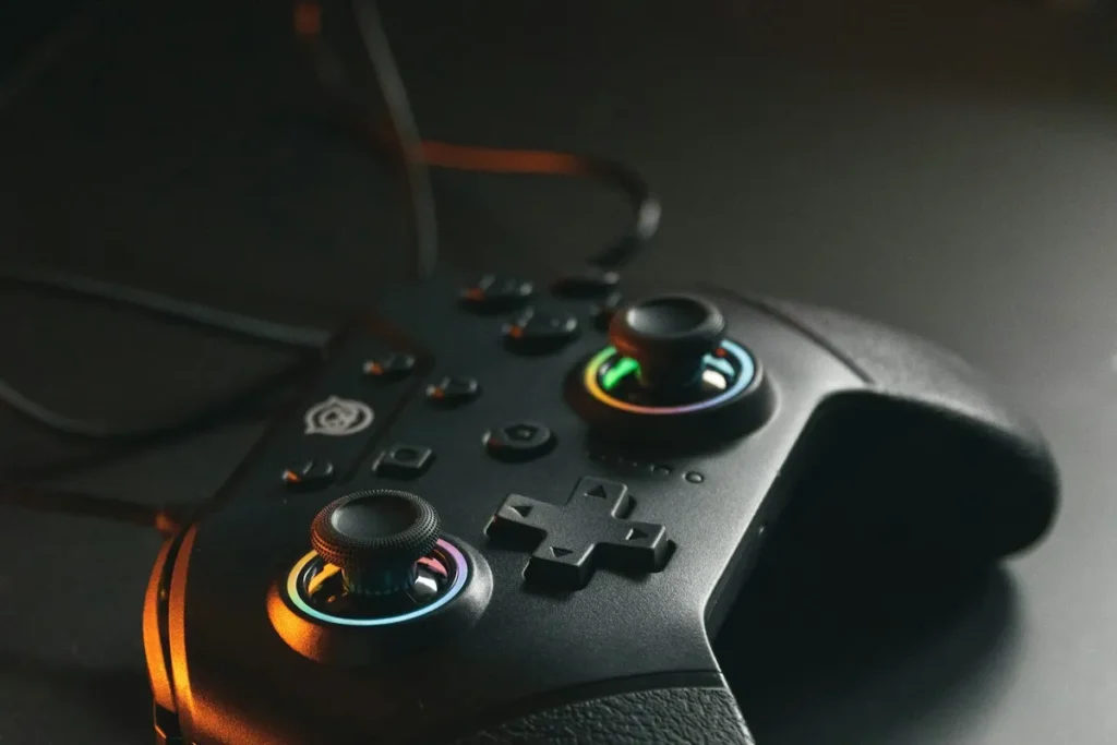 Black game controller with glowing thumbsticks on a dark desk