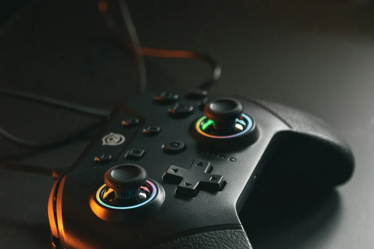 Black game controller with glowing thumbsticks on a dark desk