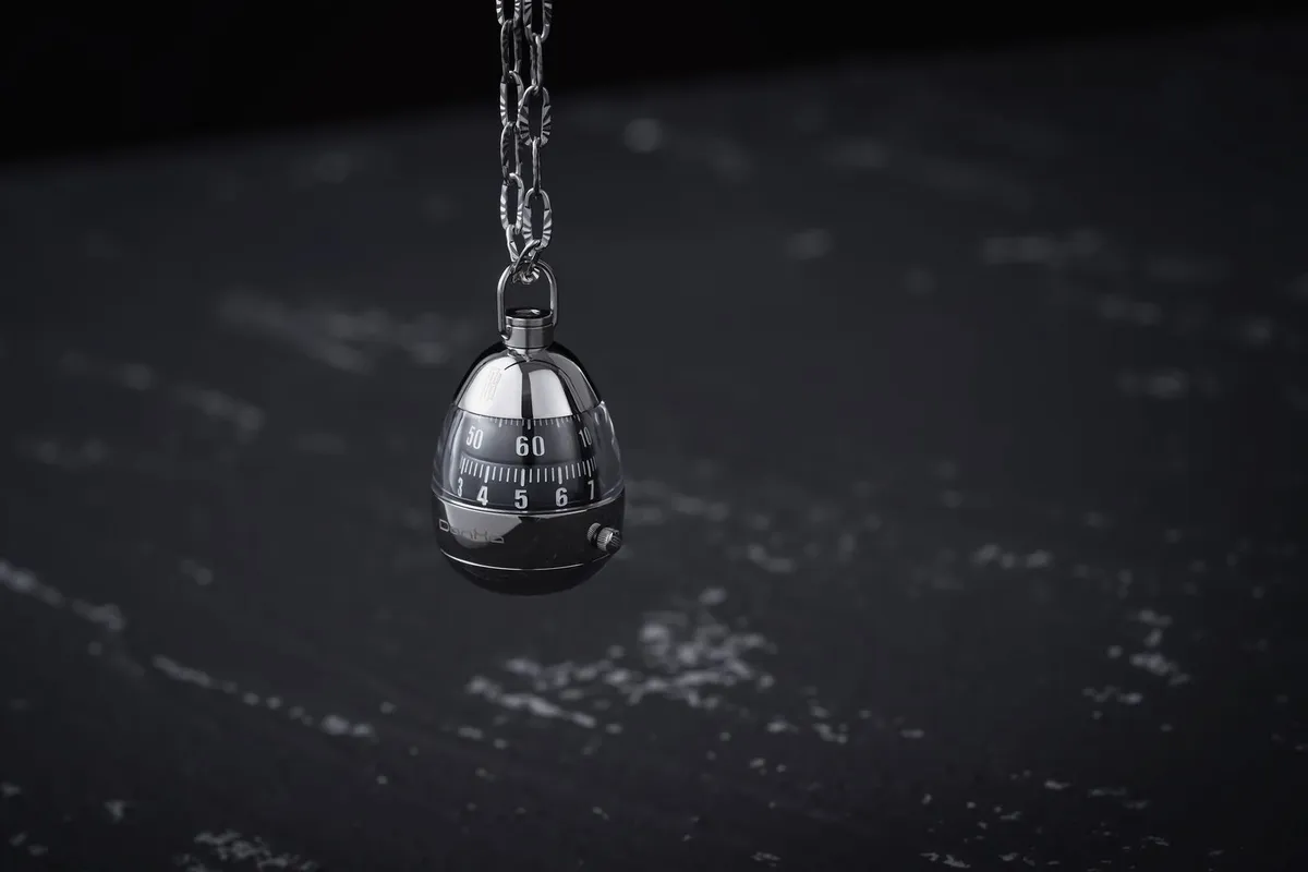 Combination lock hanging on a metal chain against a dark background